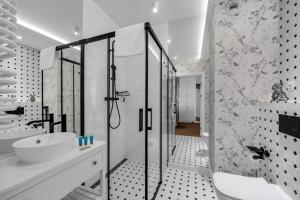 a black and white bathroom with a shower and a sink at Mehoffera Superior Apartment by BookingHost in Warsaw +25 photos