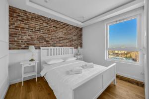 a bedroom with a white bed and a brick wall at Mehoffera Superior Apartment by BookingHost in Warsaw