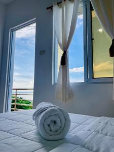 a towel laying on a bed in front of a window at Arriyus Apartelle in Maya