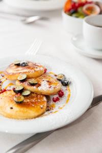 a plate of pancakes with berries and nuts on a table at Hotel Jelgava in Jelgava