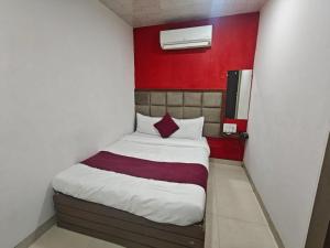 a bed in a small room with a red wall at Hotel Silver Shine Jogeshwari in Mumbai +25 photos