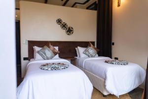 two beds in a hotel room with white sheets at The Maridadi Hotel in Moshi +91 photos