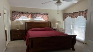 a bedroom with a bed with a red bedspread and two windows at Bayside Home With 4 Bedrooms And Elevator in North Beach Haven