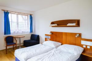 a bedroom with a bed and a chair and a table at Oaza Ricany in Ricany