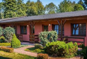 a small pink house with bushes and trees at Oaza Ricany in Ricany
