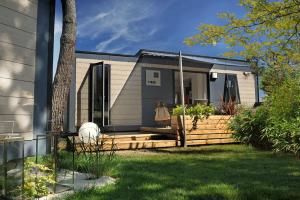 a tiny house with a wooden deck in a yard at Camping Paradis Le Grand' R in La Faute-sur-Mer