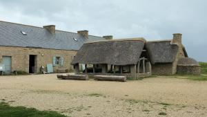 an old stone building with a thatched roof at Aux Volets Bleus in Sibiril
