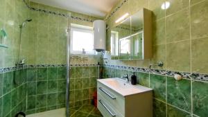 a green tiled bathroom with a sink and a shower at Apartmani Daria in Medulin +26 photos