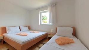 two beds in a room with a window at Apartmani Daria in Medulin