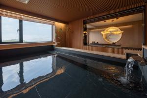 a room with a swimming pool with a mirror and a window at Mandeok Denbasta Ryokan in Busan