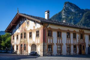 an old building with a mountain in the background at Mammhofer Suite & Breakfast in Oberammergau