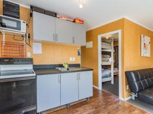 a kitchen with white cabinets and a couch in a room at Sweet Rangataua - Rangataua Bach in Ohakune +7 photos