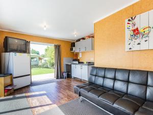 a living room with a couch and a kitchen at Sweet Rangataua - Rangataua Bach in Ohakune