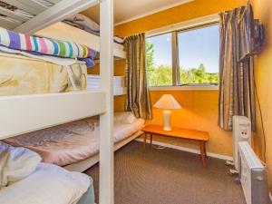 a room with two bunk beds and a table with a lamp at Sweet Rangataua - Rangataua Bach in Ohakune