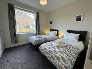 two beds in a room with a window and two lamps at Auch - Trail Cabins in Bridge of Orchy