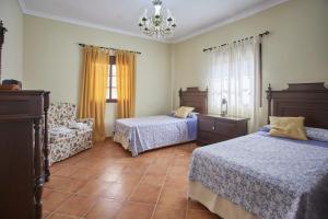 a bedroom with two beds and a chair and a chandelier at Casa Sofia in Ubrique