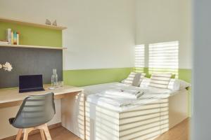 a room with a bed with a desk and a chair at I AM HOTELS Leoben in Leoben