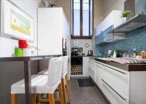 una cucina con armadietti bianchi e sgabelli bianchi da bar di Romantic Apartment Porta Venezia a Milano
