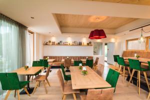 a restaurant with wooden tables and green chairs at Genuss-Pension Herti in Übelbach