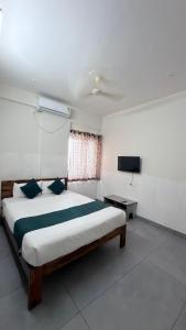 a bedroom with a bed and a flat screen tv at Lavish Hotel BG-Lodge in Bangalore