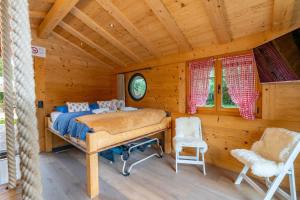 a bedroom with a bed and two chairs in a cabin at Tiny Water Villa on a Lake with shared camping bathroom in Zweisimmen