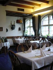 un comedor con mesas y sillas blancas y ventanas en Hotel Schmidt en Selb