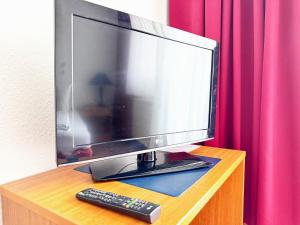 a computer monitor and a remote control on a desk at Alpha Apparthotel leipzig-Rötha in Rötha
