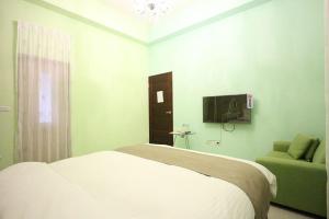 um quarto com uma cama, um sofá e uma televisão em Muses' Fantasy B&B em Taitung City