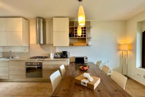 a kitchen with a wooden table with white chairs at Villa Aurelia in Plesio