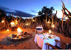 een eettafel met 's avonds verlichting op het strand bij Jock Safari Lodge in Skukuza