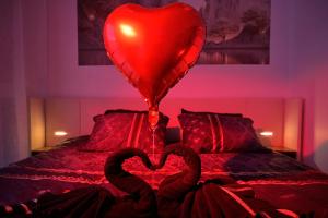 two heart shaped swans sitting on a bed with a balloon at Echappée Nocturne in Saint-Privat