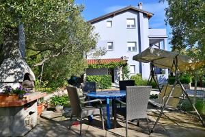 a blue table and chairs in a yard with a white house at apartmani Novotny crveni in Banjol