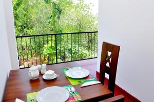 una mesa de madera con platos en el balcón en Little Swan Guest house en Bentota