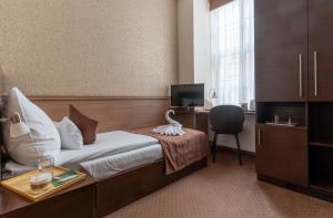 a hotel room with a bed with a desk and a chair at Central Hotel 21 in Budapest