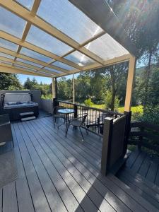 a deck with a pergola and a table and chairs at River Cottage Hot tub spa in Drumnadrochit