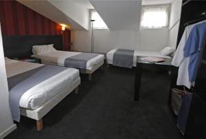 Habitación de hotel con 2 camas y escritorio en Hôtel Alizé en Cannes
