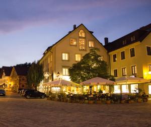 a building with tables and umbrellas in front of it at Hotel Drei König in Immenstadt im Allgäu