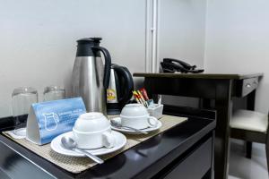 a counter with cups and saucers and a coffee maker at Annex Lumpini Bangkok in Bangkok