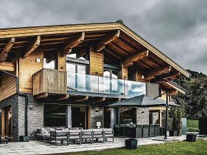 a house with a balcony with chairs and an umbrella at Chalet Amadeus by we rent in Piesendorf