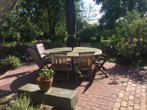 a patio with a table and chairs and an umbrella at Demeure Saint Gildas in La Haye-Pesnel