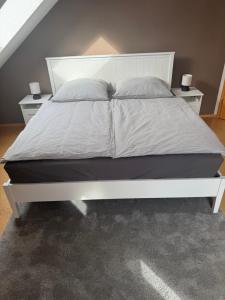 a white bed in a bedroom with two night stands at Ferienzimmer Schürer in Lauter