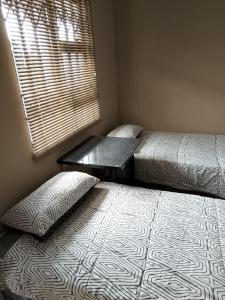 a room with two beds and a window and a table at AMASHIYA flats in Richards Bay