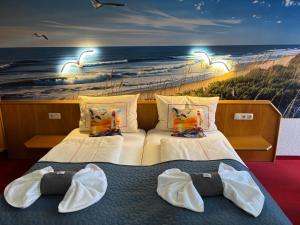 two beds in a room with a painting of the beach at Ambiente Hotel Strehla in Strehla