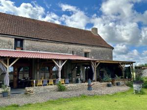 a large brick building with a porch and chairs at La Ferme de Tart in Verdonnet +30 photos
