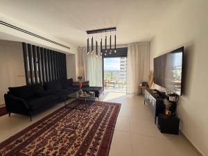 a living room with a black couch and a flat screen tv at שלוות העמק - דירת 3 חדרי שינה במיקום מרכזי in Ganne Tiqwa