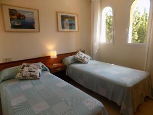 two beds in a room with two windows at Casa Jazmin in Cala Bona