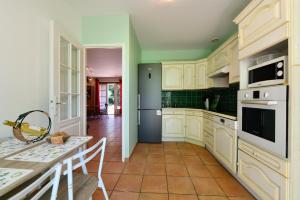 a kitchen with white cabinets and green walls and a table at Le mouly/grand gite in Miossens-Lanusse +26 photos