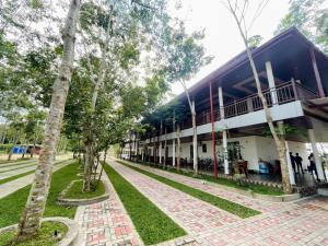 a building with a brick sidewalk and trees in front at Yaalu-Yaalu in Welikanda