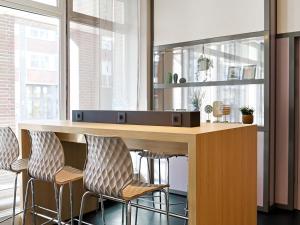 a kitchen with a bar with three stools at B&B Hotel Bremen-Altstadt in Bremen