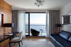 a living room with a couch and a large window at Amadria Park Hotel Royal in Opatija